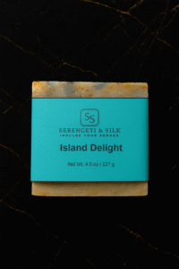 Serengeti & Silk Island Delight handmade soap bar with golden and teal tones on black background.